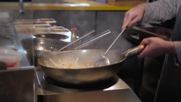 Шеф-повар бросает жареные овощи в сковородку, коммерческая кухня кулинария — стоковое видео