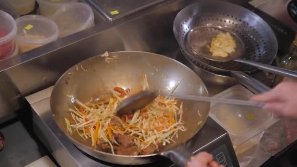 Koch wirft gebratenes Gemüse mit Fleisch in die Pfanne, gewerbliche Küche Kochen — Stockvideo