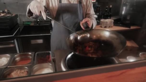 Шеф-повар бросает жареные овощи с мясом в сковородке, коммерческая кухня приготовления пищи — стоковое видео