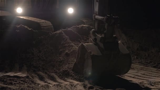 Excavadora excavación de arena y polvo de trabajo durante las obras de carretera en la noche, Primer plano tiro de cubo de una máquina excavadora de movimiento de tierra, Trabajo nocturno, horas extras — Vídeo de stock