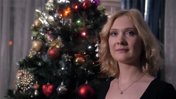 Bella giovane donna con capelli biondi vicino all'albero di Natale a casa — Video Stock