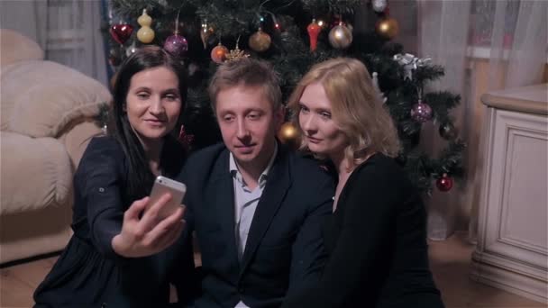 Ομάδα νέων ανθρώπων, καθιστώντας Selfie κοντά στο χριστουγεννιάτικο δέντρο. Ευτυχισμένο το νέο έτος γιορτή έννοια — Αρχείο Βίντεο