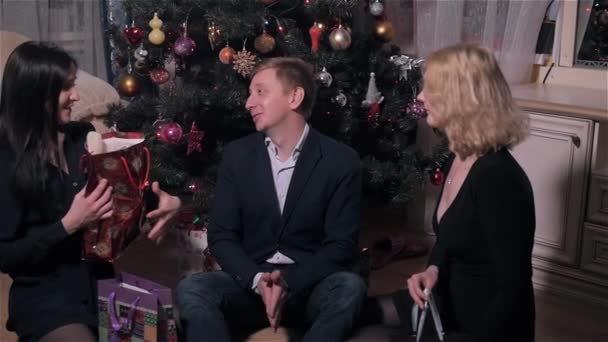 Группа молодых людей дарит подарки друг другу под елкой в новогоднем интерьере, в новогоднем празднике — стоковое видео