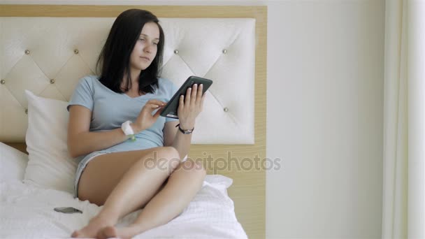 使用 Tablet Pc 在早上躺在床上的黑发少女 — 图库视频影像