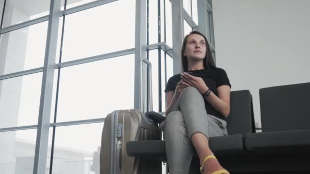 Jeune jolie femme d'affaires utilisant un smartphone à l'aéroport en attendant sa file d'attente pour l'inscription, concept de voyage — Video