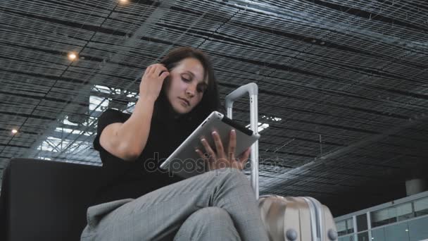 Jeune jolie femme d'affaires utilisant une tablette PC à l'aéroport en attendant sa file d'attente pour l'enregistrement, concept de voyage — Video