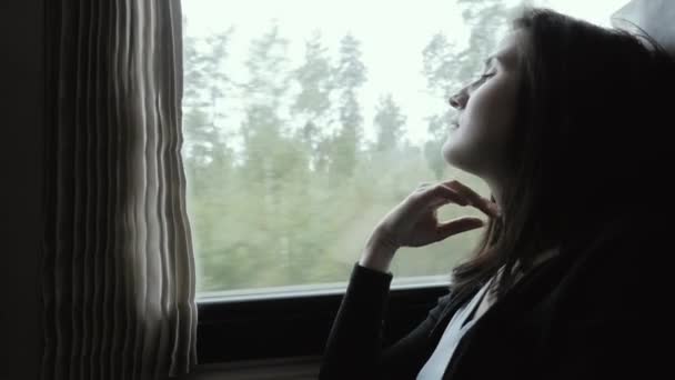 Mulher atraente em pensamento olhando para fora de uma janela de trem, câmera lenta, conceito de viagem — Vídeo de Stock