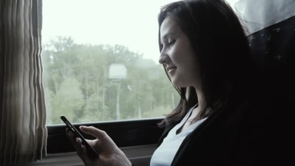 Woman Using Smartphone Next to Window in Moving Train, Travel Concept — Stock Video