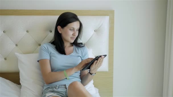 使用 Tablet Pc 在早上躺在床上的黑发少女 — 图库视频影像