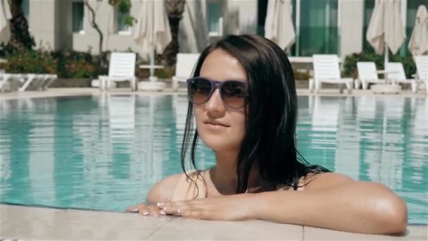 Jeune belle femme brune dans les lunettes de soleil profite de l'eau dans la piscine — Video