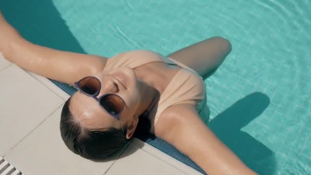 Jovem bela morena mulher em óculos de sol goza de água na piscina — Vídeo de Stock