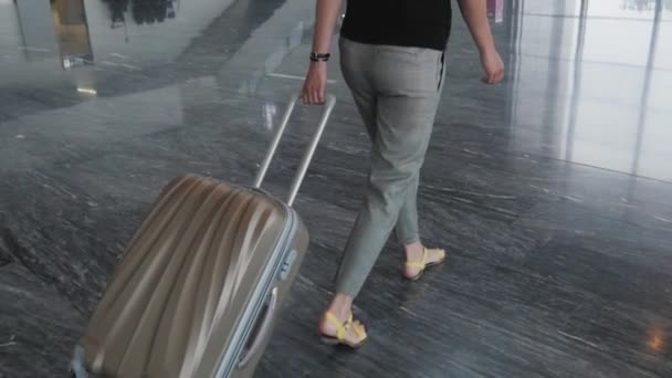 Giovane bella donna d'affari a piedi in aeroporto con il suo bagaglio in attesa della sua coda per la registrazione, concetto di viaggio — Video Stock