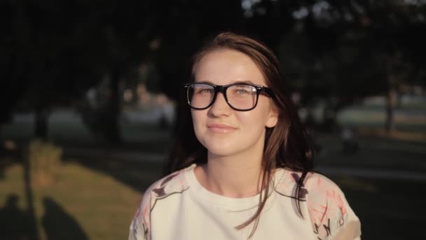 Al aire libre retrato de hermosa joven morena chica en gafas, bastante linda mujer sonriente en el parque al aire libre al atardecer — Vídeos de Stock