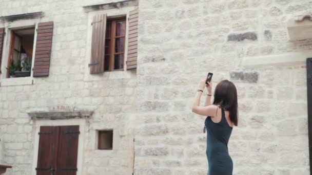 Yong kvinna att ta bilder av Smartphone. Snygg sommar resenären kvinna med telefonen utomhus i Europeiska stad, gamla stan i bakgrunden — Stockvideo