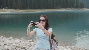 Genç kadın Selfie yanında Smartphone dağ gölü önünde alarak. Bir dağ ormanda vakit güzel beyaz kız