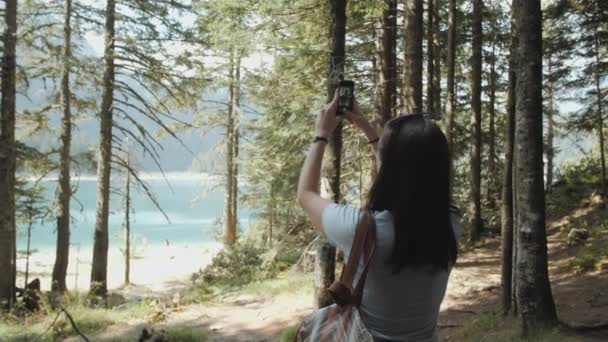 Mulher jovem tirando foto por Smartphone na frente de Mountain Lake. Menina branca bonita que gasta o tempo em uma floresta do moutain — Vídeo de Stock