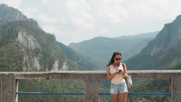 Turist flicka med Smartphone stående på den bron Djurdjevic i Montenegro, resa livsstil — Stockvideo