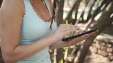 Güneşli bir günde bir parkta bir bankta oturmuş, On-line alışveriş kavramı bir Tablet Pc ile güzel neşeli kız