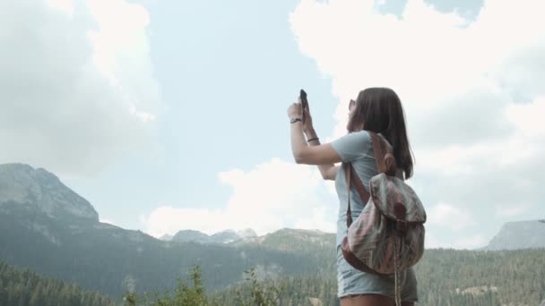 Fiatal nő figyelembe fotó: Smartphone előtt hegyi tó. Tölteni az időt a hegyre néző erdő gyönyörű kaukázusi lány — Stock videók
