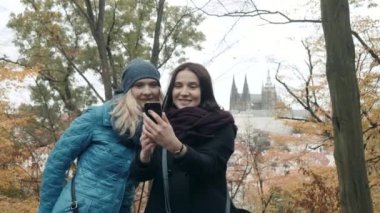 İki güzel ve mutlu bir genç kadın yapma Selife sonbahar Park içinde hareket eden telefon ile. Arkadaşlarım Selfie olun