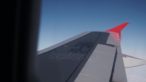 Venster weergave van het formulier-vliegtuig, en keek uit het raam van een vliegtuig naar de vliegtuig vleugel, de blauwe lucht en de wolken — Stockvideo