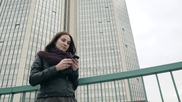 Attraktiv turist iklädd fritidskläder applikationen på Smartphone för att navigera i stan, Hipster flicka som står på Urban miljö promotion bakgrund textning meddelanden via mobiltelefon — Stockvideo