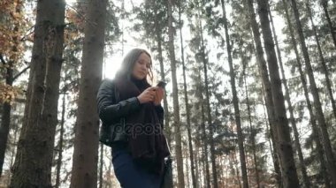 Sonbahar parkta Smartphone kullanan güzel genç esmer kadın. Kız ormanda yürüyüş sonbaharda, yaşam kavramı