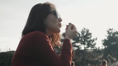 Mutlu genç kadının güneşli bir günde çim parkta oturan bir dondurma