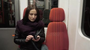 Mesaj yazarak metro treninin cep telefonu, akıllı telefon ile esmer kadın üzerinde genç bir kadın portresi