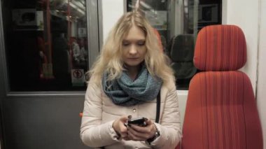 Mesaj yazarak metro treninin cep telefonu, akıllı telefon ile sarışın kadın üzerinde genç bir kadın portresi