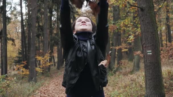 Porträtt av en glad ung kvinna leker med hösten lämnar i skogen — Stockvideo