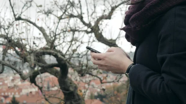 Primer plano de las manos de las mujeres usando el teléfono inteligente sentado en el banco en el parque. Hermosa chica europea mensajes de texto en el teléfono — Foto de Stock