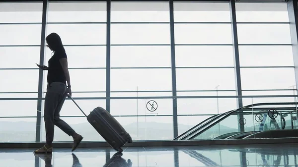 Junge hübsche Geschäftsfrau mit einem Smartphone am Flughafen, während sie auf ihre Registrierung wartet, Reisekonzept — Stockfoto