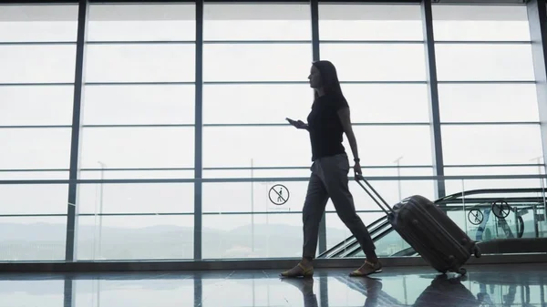 Giovane bella donna d'affari utilizzando uno smartphone in aeroporto in attesa della sua coda per la registrazione, Viaggiare concetto Immagine Stock