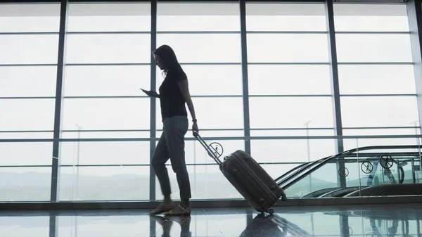 Молода красива бізнес-леді, використовуючи смартфон в аеропорту, чекаючи її черги для реєстрації, концепція подорожі Стокова Картинка