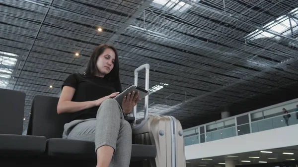 Молода красива бізнес-леді, використовуючи планшетний ПК в аеропорту, чекаючи її черги для реєстрації, концепція подорожі Стокове Зображення