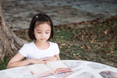küçük Asyalı çocuk açık bir kitap okuma