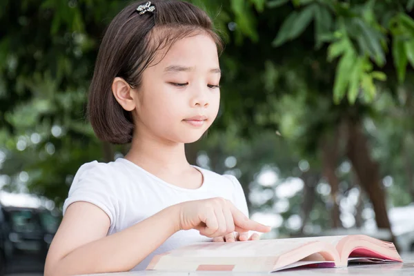 küçük Asyalı çocuk açık bir kitap okuma