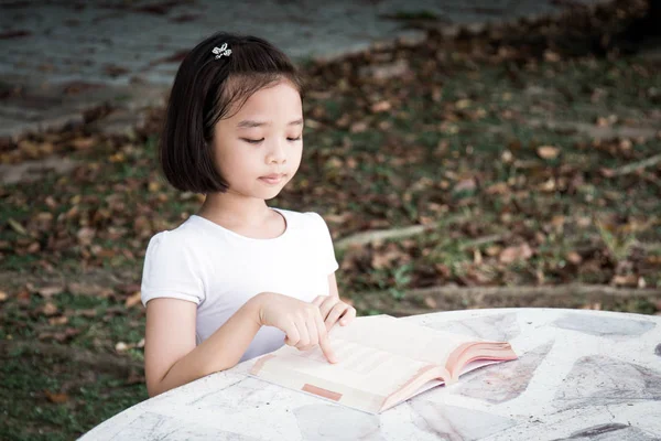 küçük Asyalı çocuk açık bir kitap okuma
