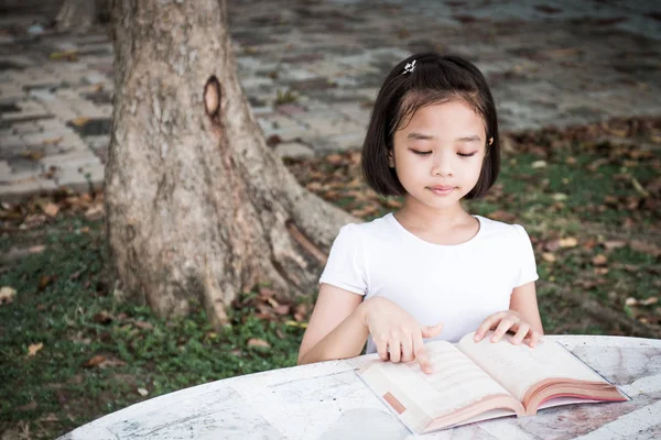 küçük Asyalı çocuk açık bir kitap okuma