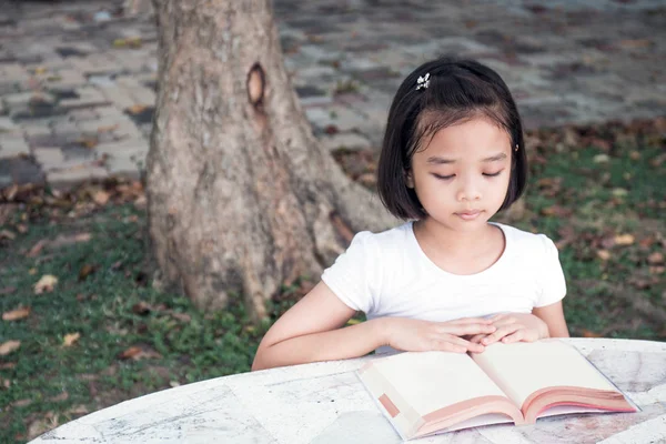 küçük Asyalı çocuk açık bir kitap okuma