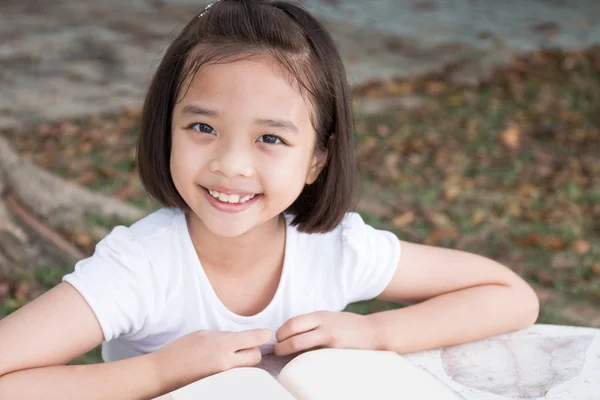 Mutlu küçük Asyalı çocuk açık bir kitap okuma