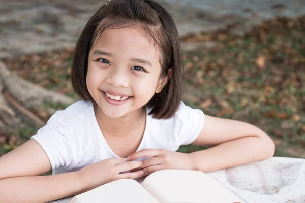 Mutlu küçük Asyalı çocuk açık bir kitap okuma