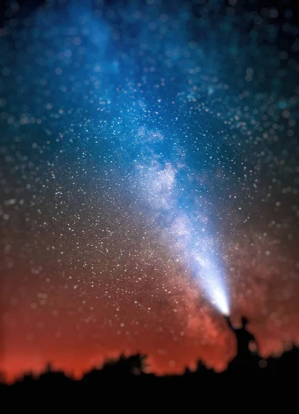 Silueta de un hombre con una linterna sobre un fondo del cielo Imagen de archivo