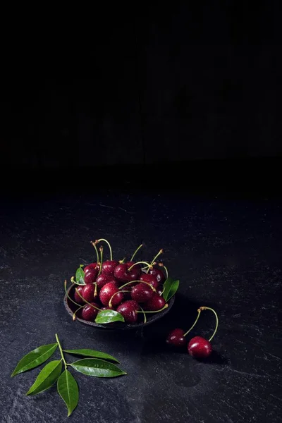Färska körsbär i svart skål — Stockfoto