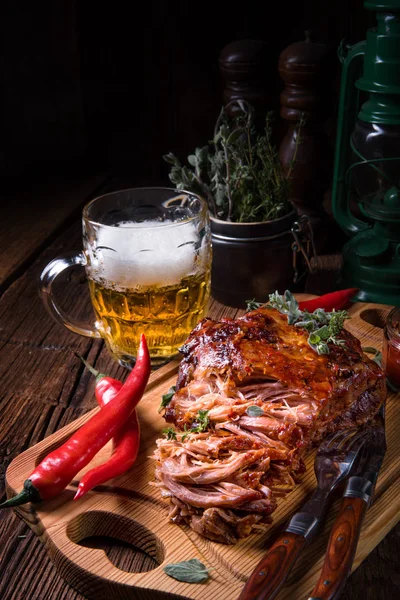 beer and tasty Barbecue pulled pork on wooden cutting board