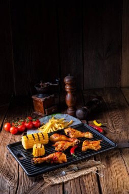 Rustik ızgara tavuk kanatlar, bacaklar ve baharatlı Mısır