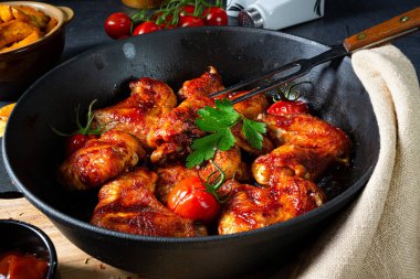 Baharatlı tavuk kanatları ve patates dilimleri.