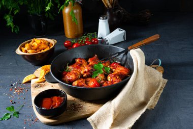 Baharatlı tavuk kanatları ve patates dilimleri.