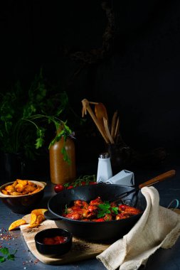 Baharatlı tavuk kanatları ve patates dilimleri.